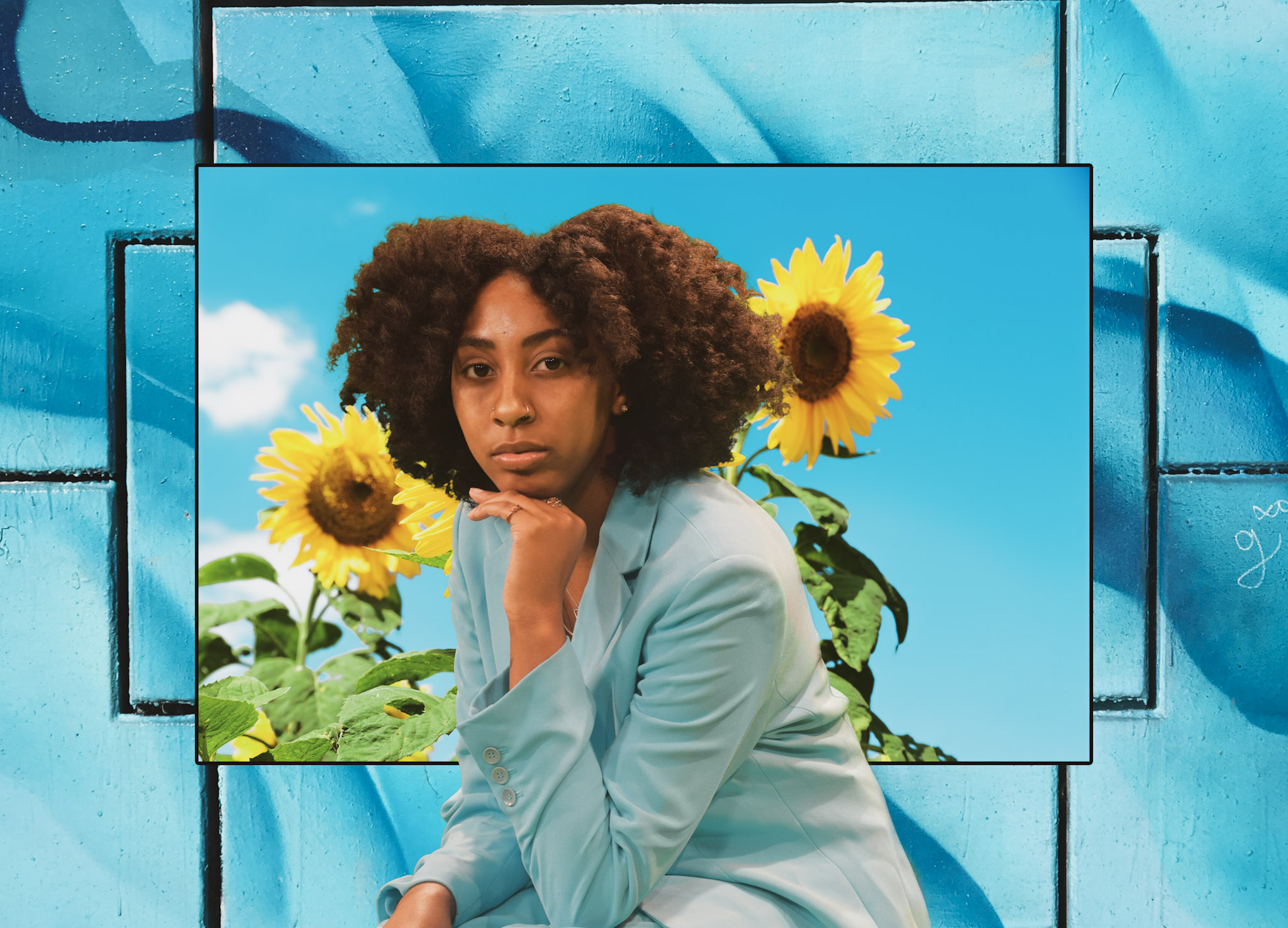 A woman rests her head on her hand as she looks into the camera