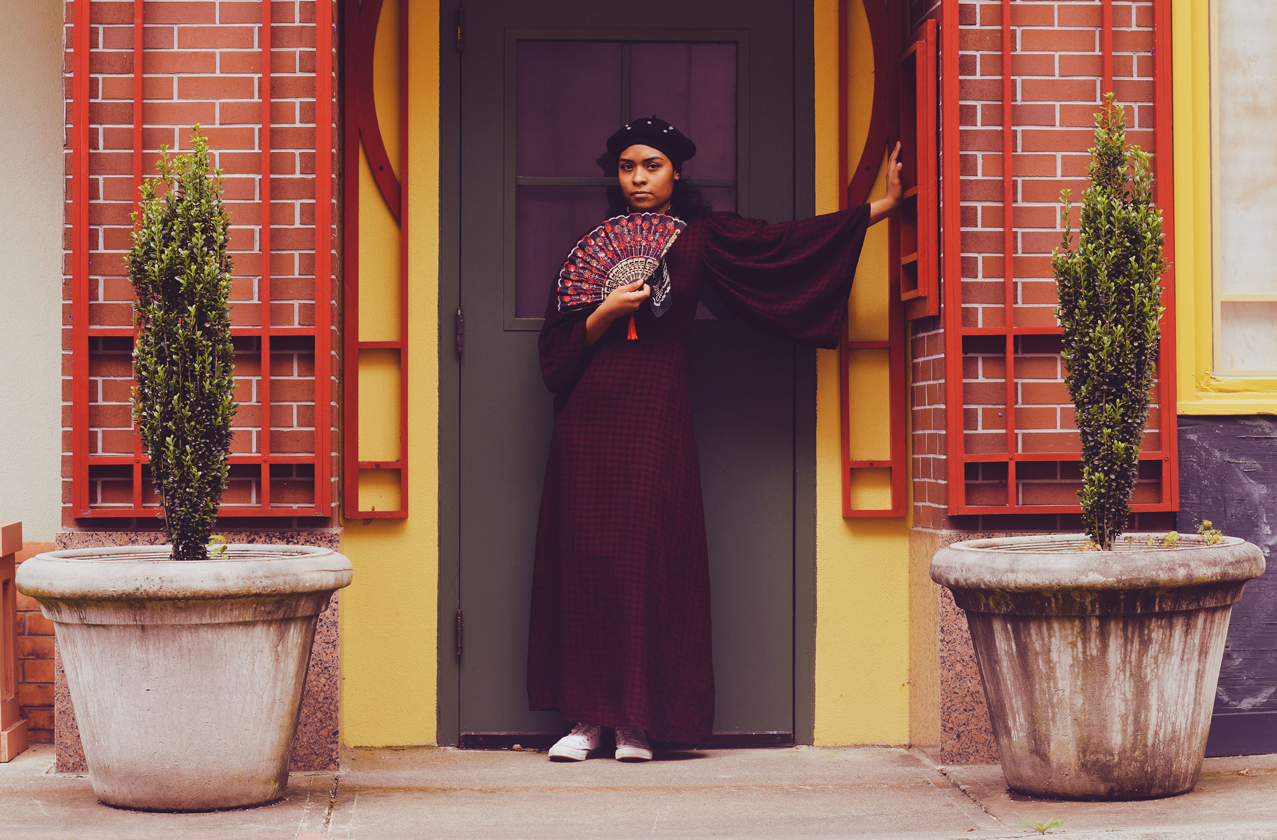 A woman holds a fan while looking at the camera