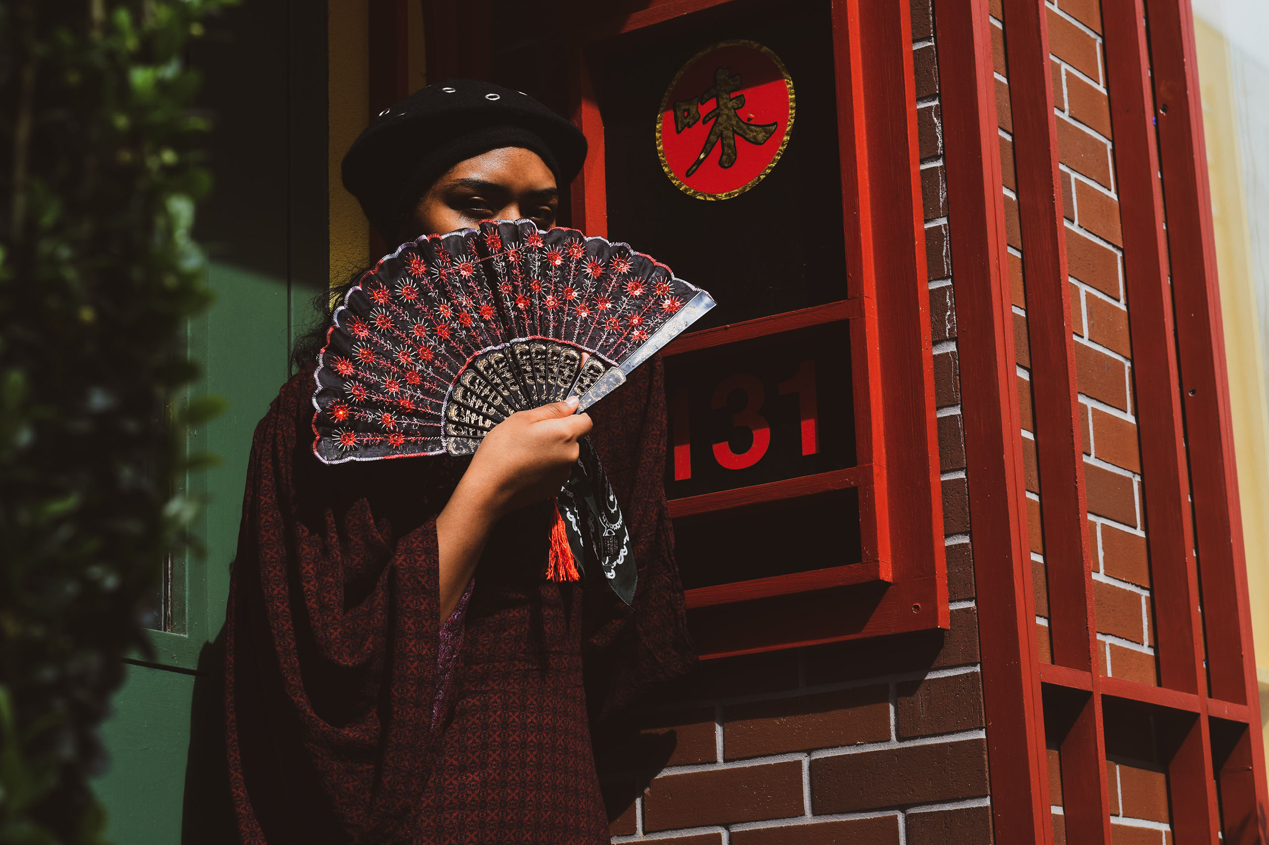 A woman holding a fan over her face.